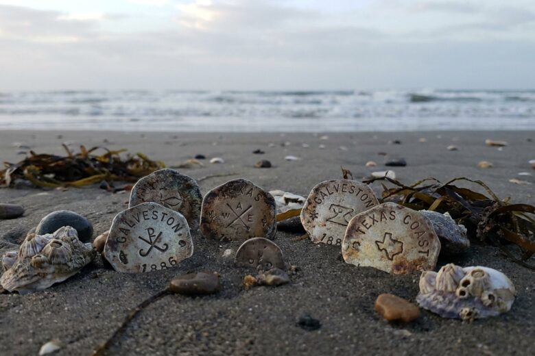Handcrafted metal tokens discovered on Texas beach sand with coastal debris
