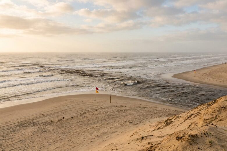 Rip current visible as darker channel cutting through breaking waves on Texas beach