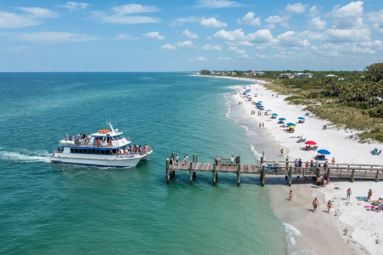 Passenger ferry arriving at beach dock with beachgoers and coastal scenery